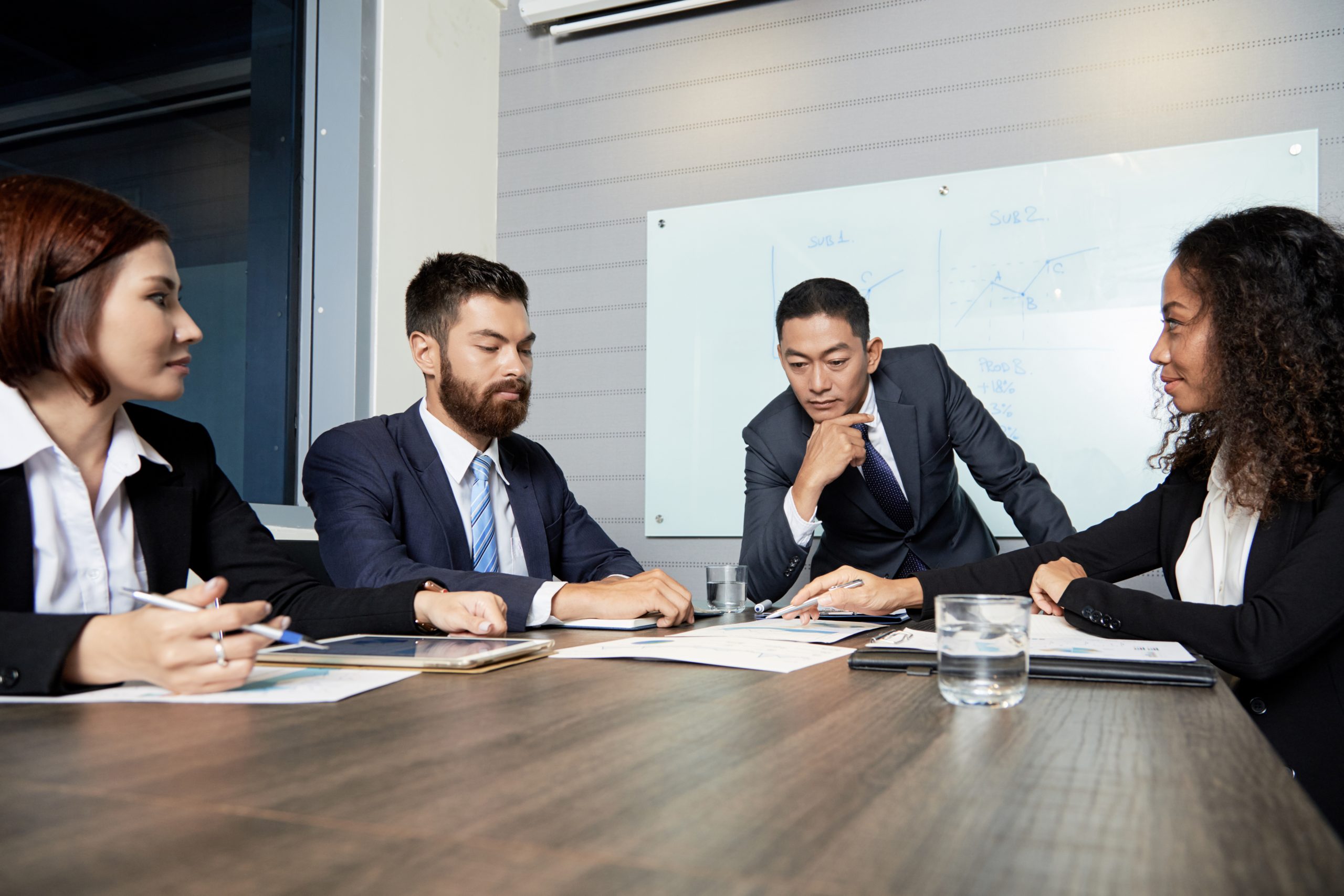 Group of diverse men and women gathering at table in office and having discussion